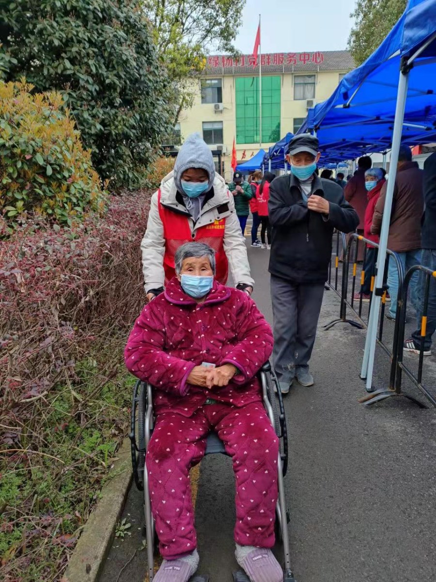 孫欣幫助核酸檢測(cè)現(xiàn)場(chǎng)腿腳不便的老人.jpg
